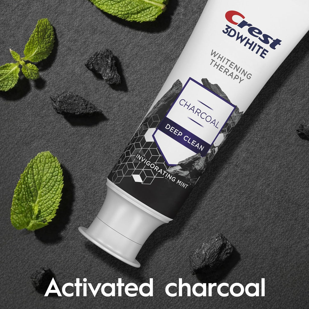 Crest 3D White Whitening Therapy Charcoal Deep Clean toothpaste tube with activated charcoal and mint leaves on a dark background.