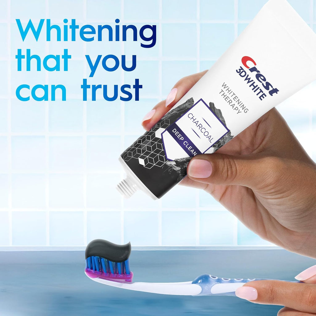 Crest 3D White toothpaste with charcoal deep clean and a toothbrush on a blue background.